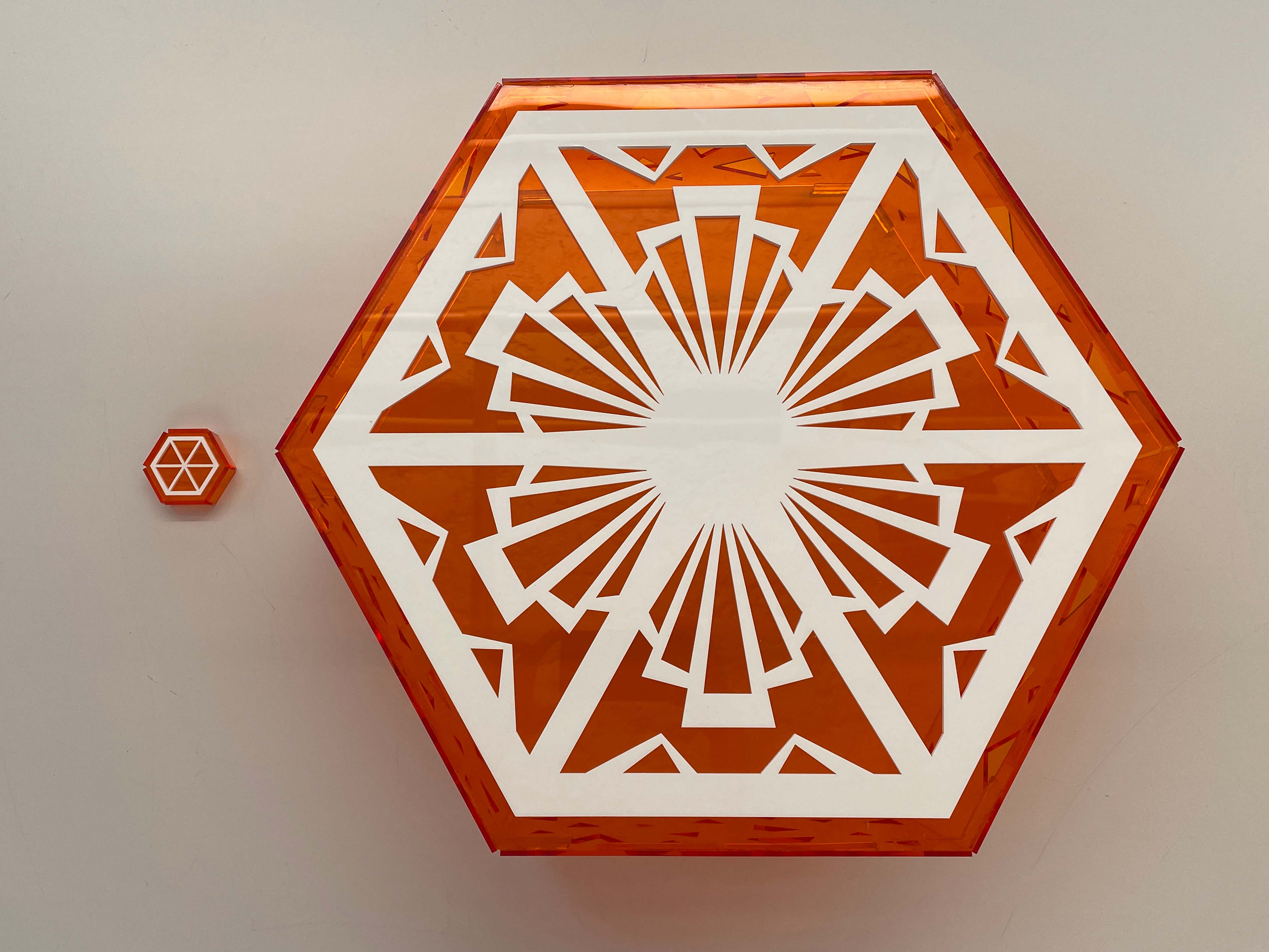 an image with a top view of the small less detailed orange to the left of the big more intricate orange, both are mainly orange with white detailing